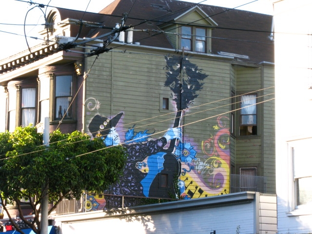 the view of a building and street with a mural on the side of it