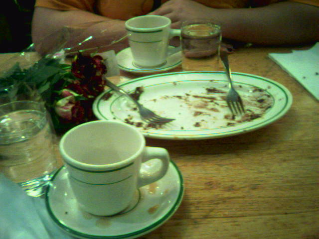 the dirty table has plates and cups with a broken fork