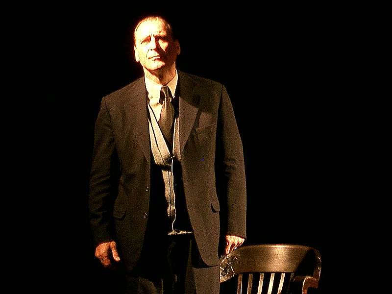man posing for picture near chair on stage