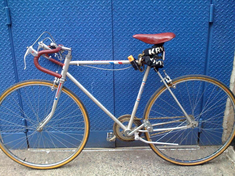 the bicycle is parked beside a blue wall