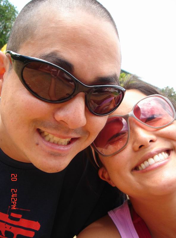 a woman smiling and leaning against the face of a man with sunglasses on