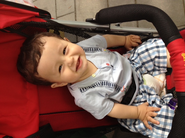 a toddler sitting in a stroller with red items