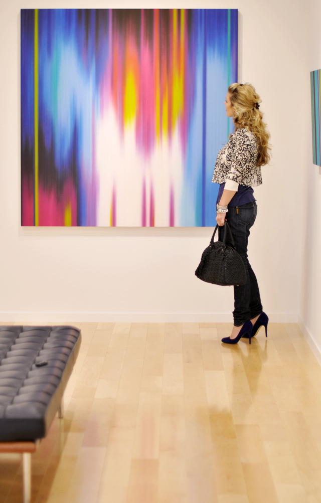 a woman standing in front of a painting while holding a purse