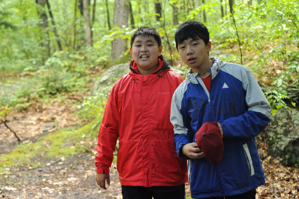 two boys standing together in the woods