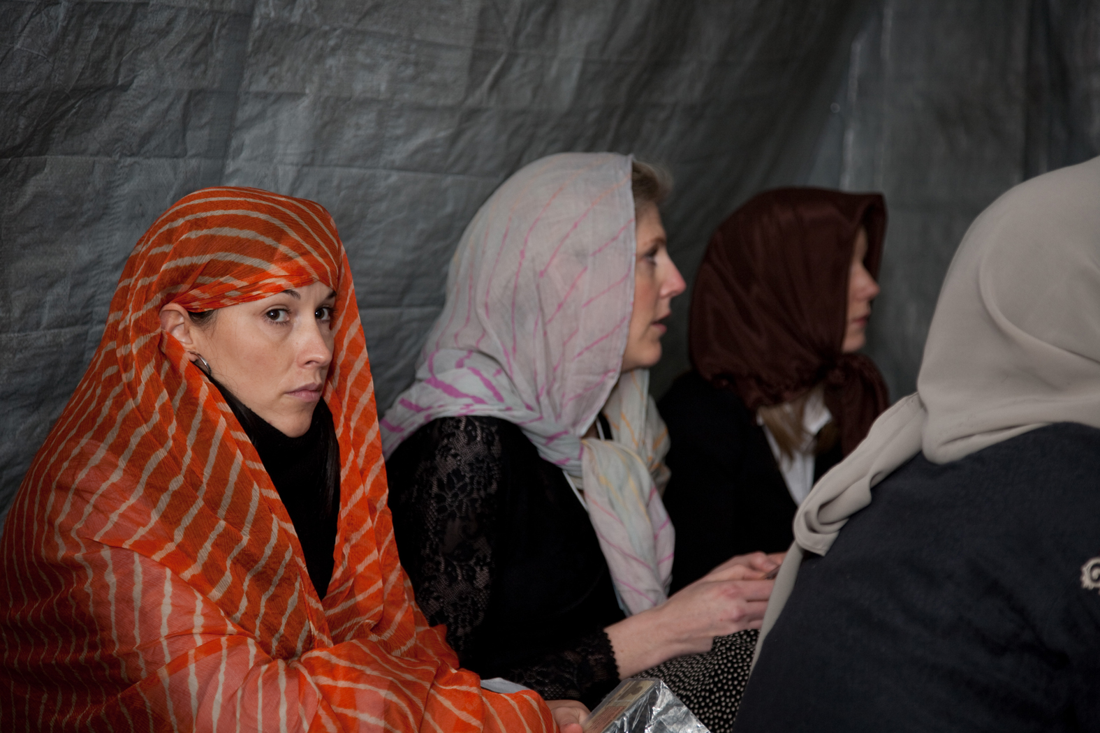 several women wearing headscarves and scarves looking at soing