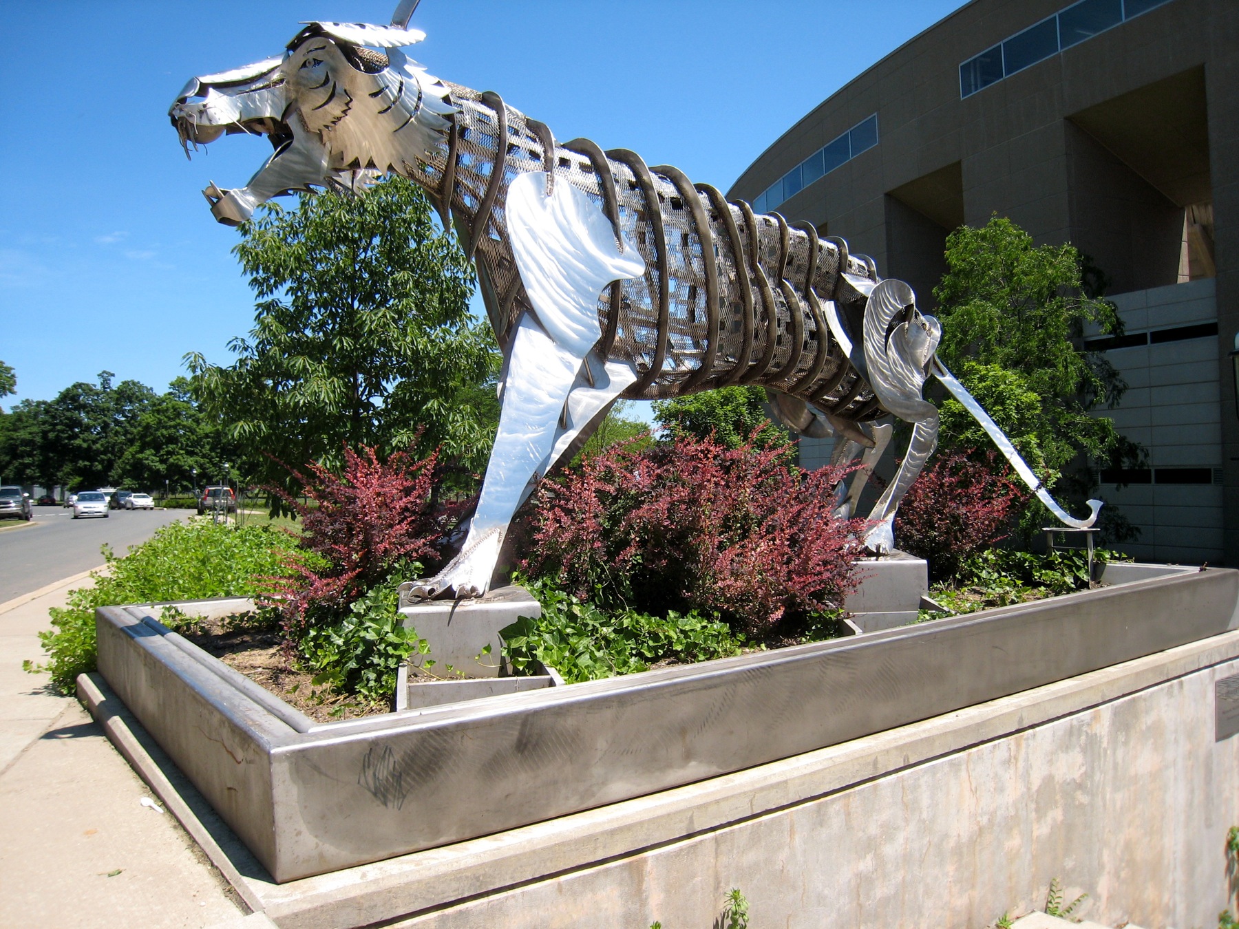 a large metal dog sculpture is outside near a building