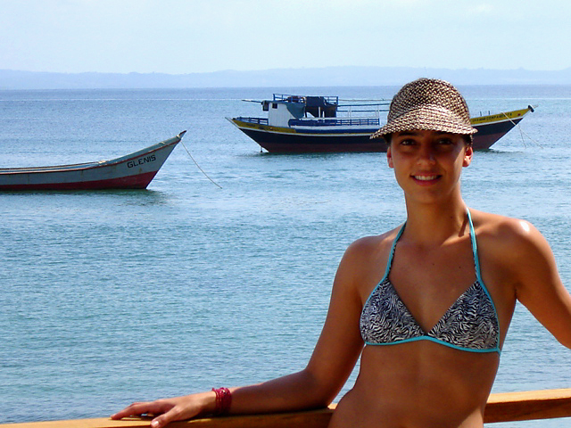 a young woman in a bikini stands by a pier