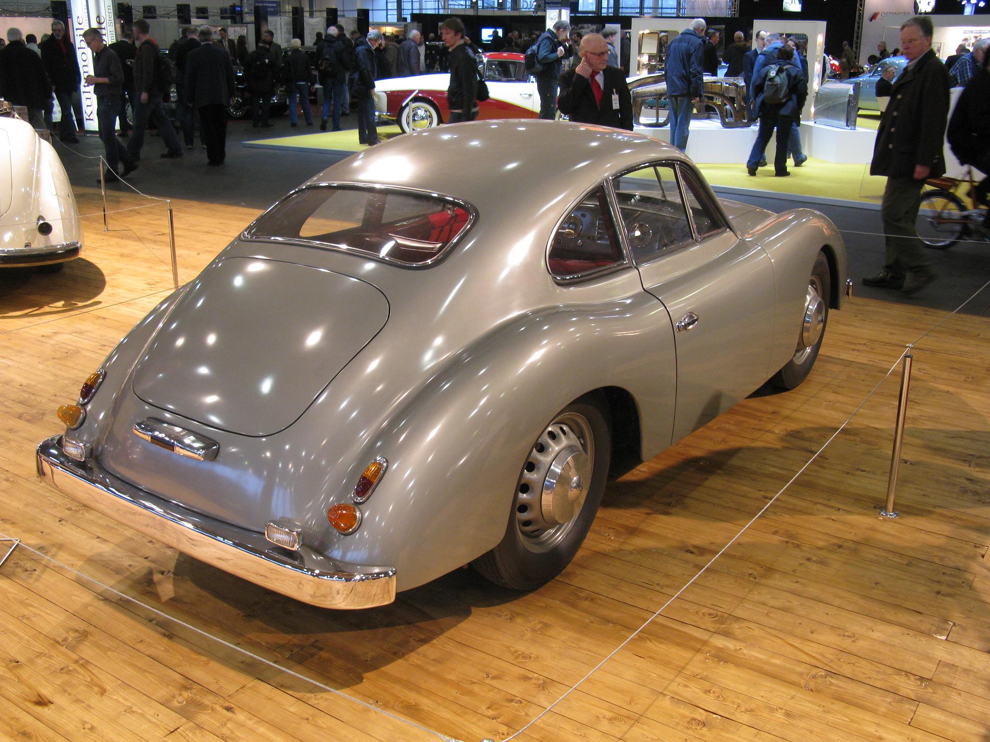 a gray sports car in the center of a wooden floor