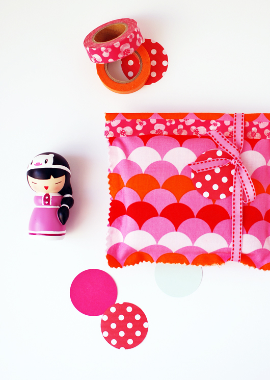 pink wrapping paper, some polka dots and a little doll are sitting on a table