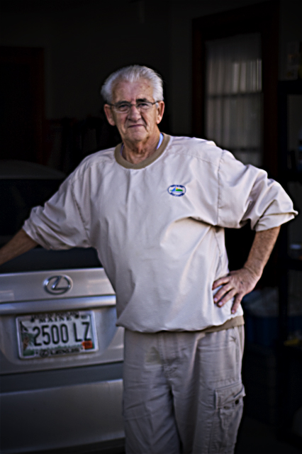 an elderly man is leaning on a car