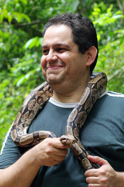 a man is holding a large snake in his arms