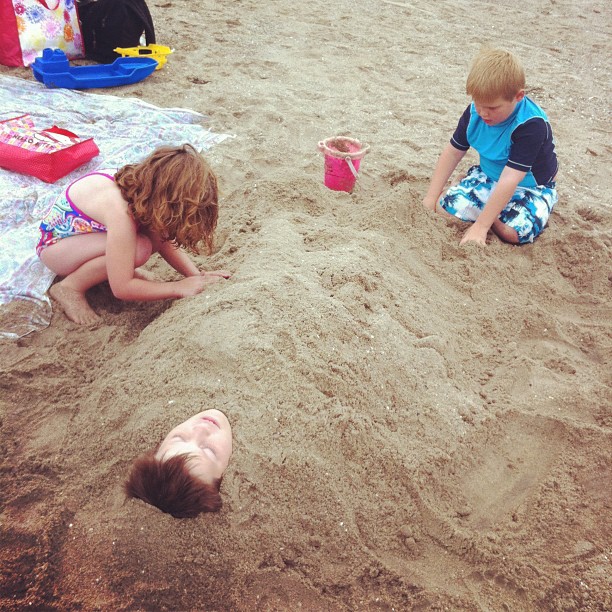 two young children play in the sand on a beach