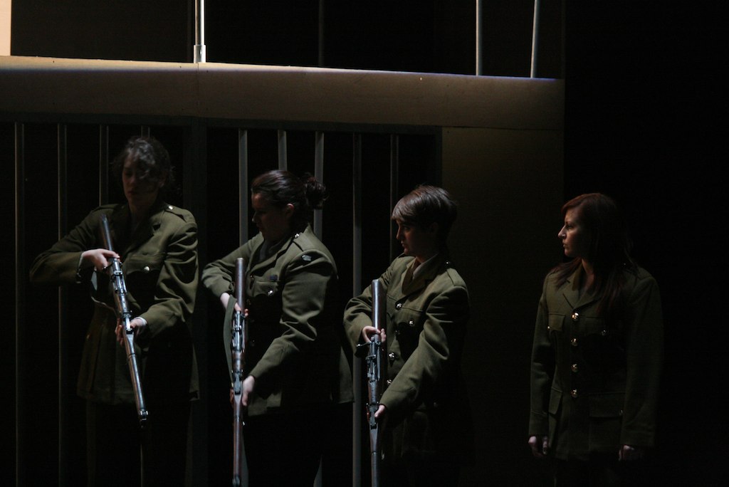three soldiers stand in front of bars holding the batons