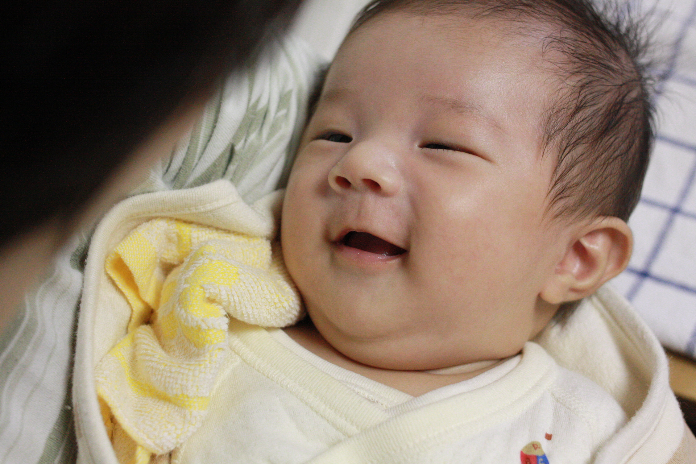 a baby smiles in his swaddled outfit