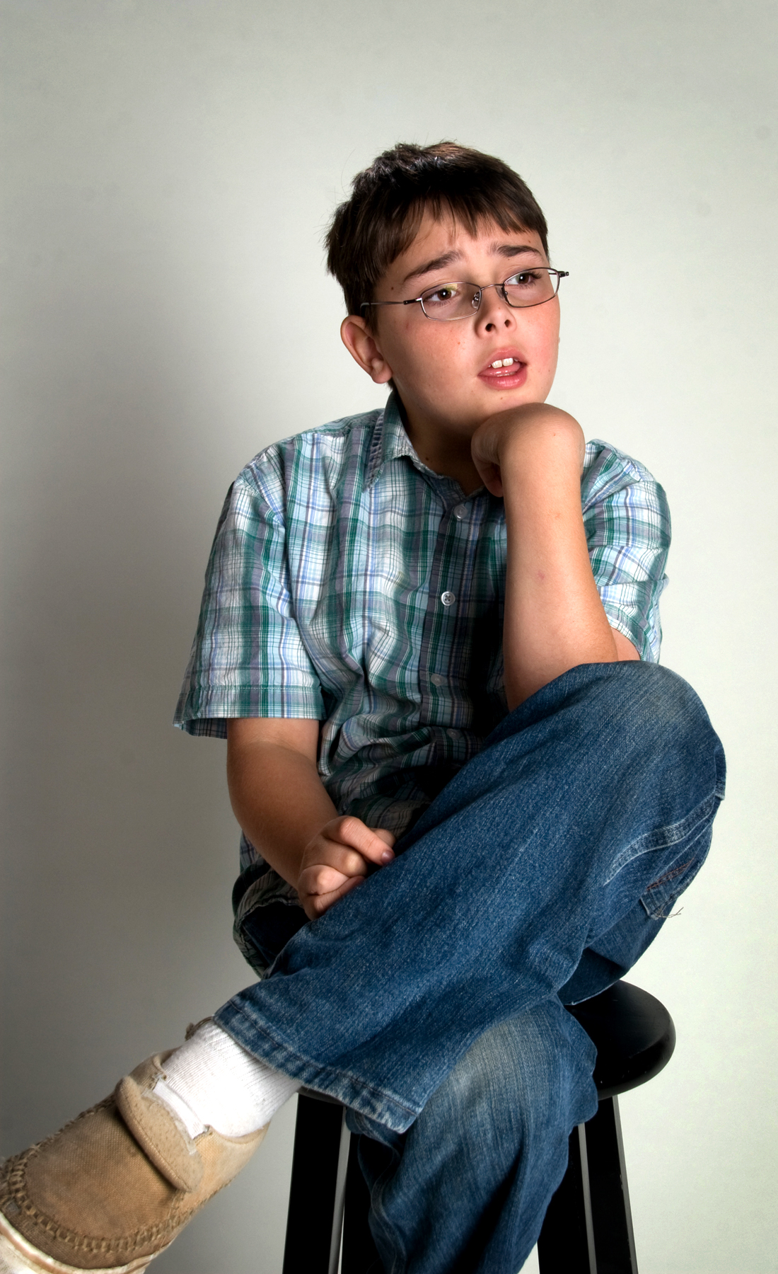 a young man sitting down posing with his legs crossed