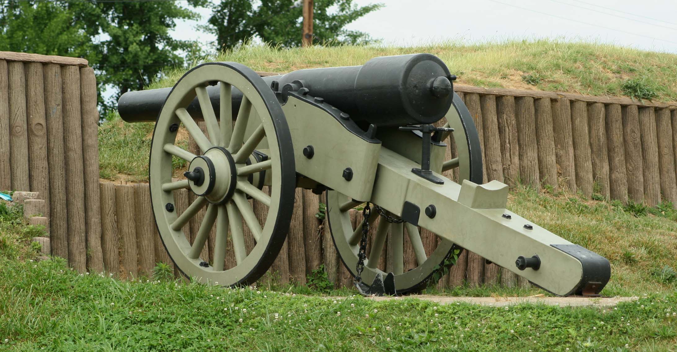 an old cannon leaning on the fence of a wooden fence