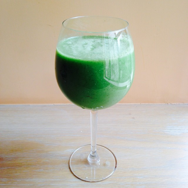 a green beverage in a glass sitting on top of a table