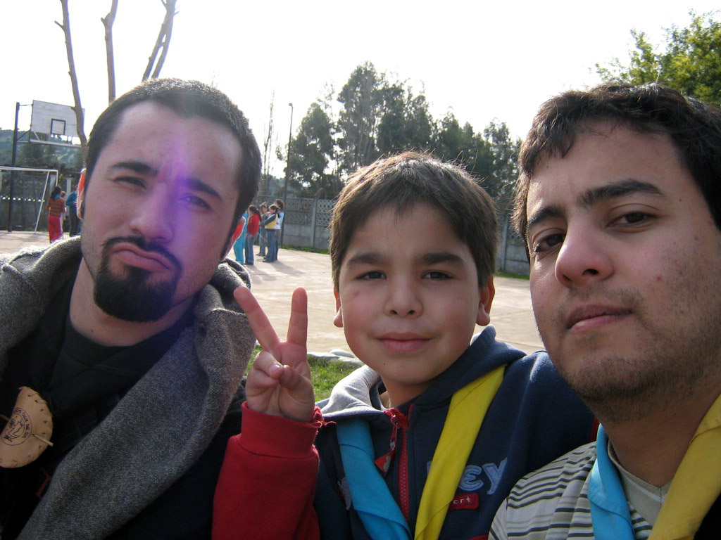 three men and one boy standing together, showing peace sign