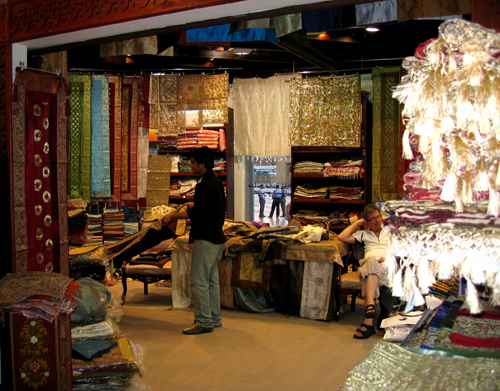 people look at clothes and rugs for sale in a store