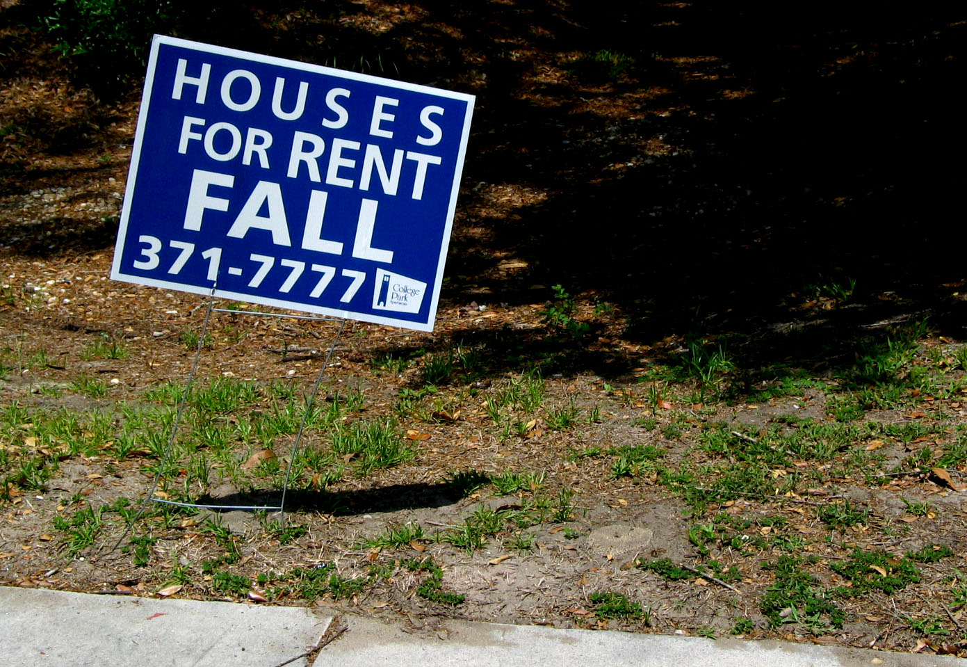 a blue sign on the ground in front of a house