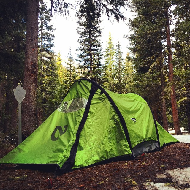 a green tent sitting in the middle of the forest