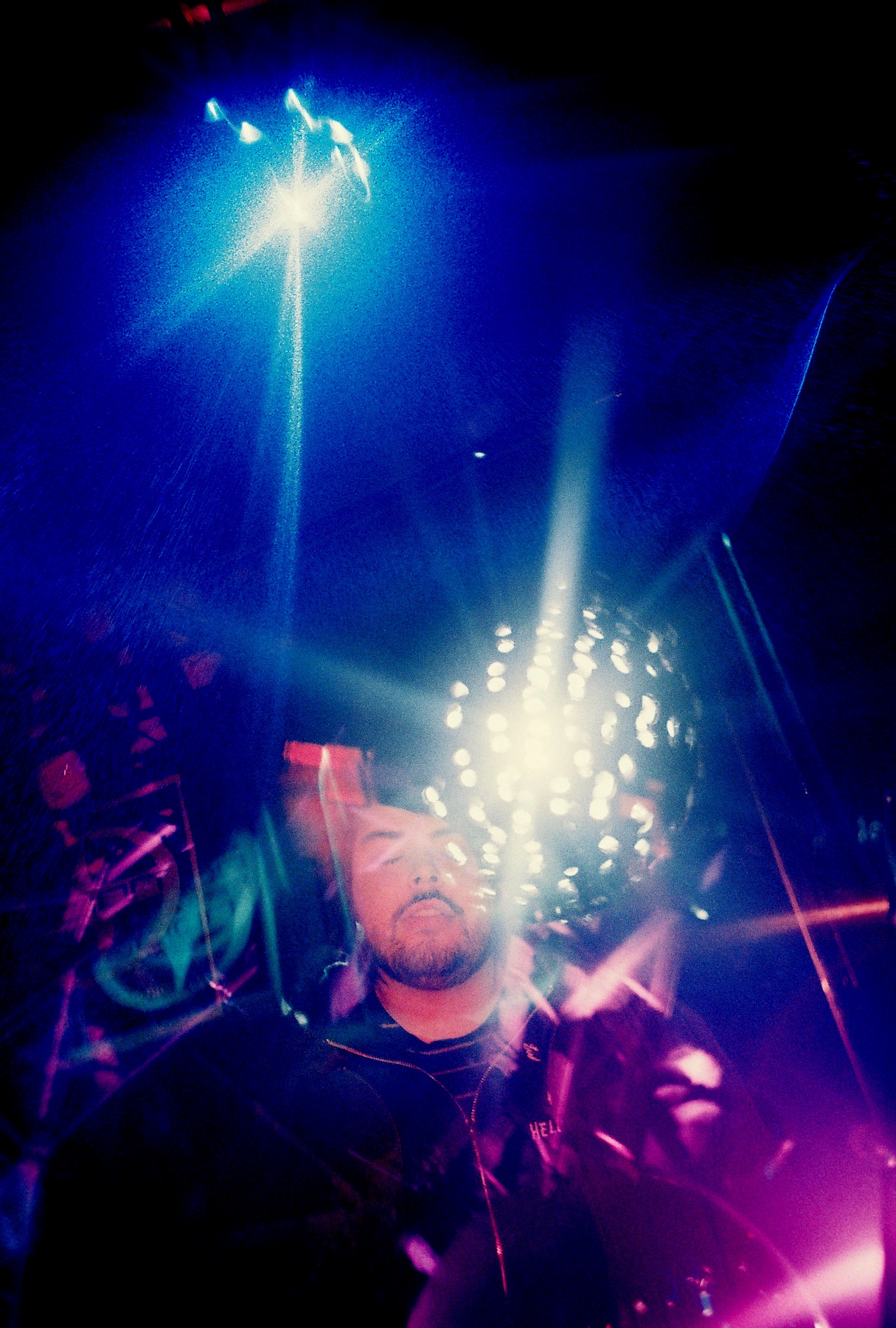 bright beams shining from behind the head and arm of a drummer on stage