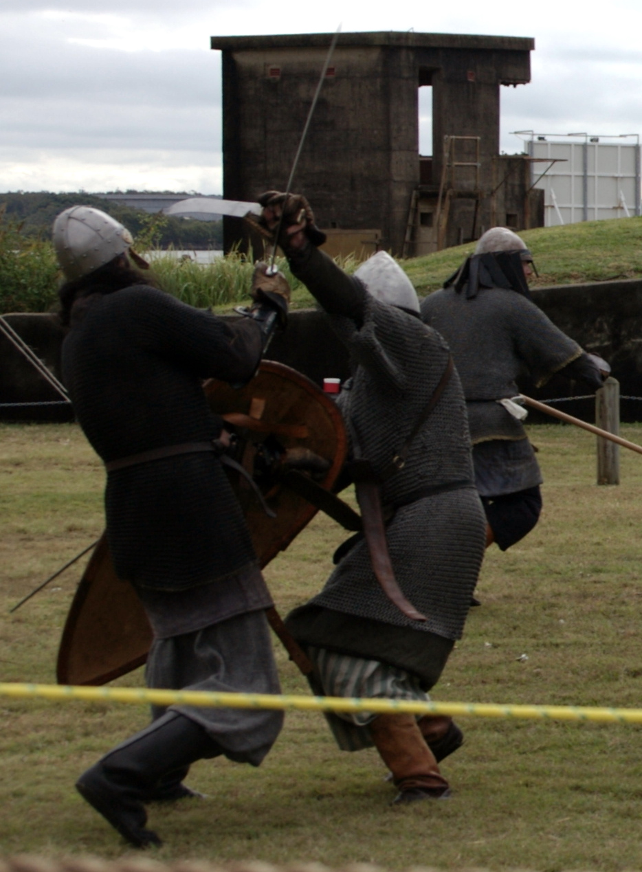 three men dressed as knights fighting in front of a structure