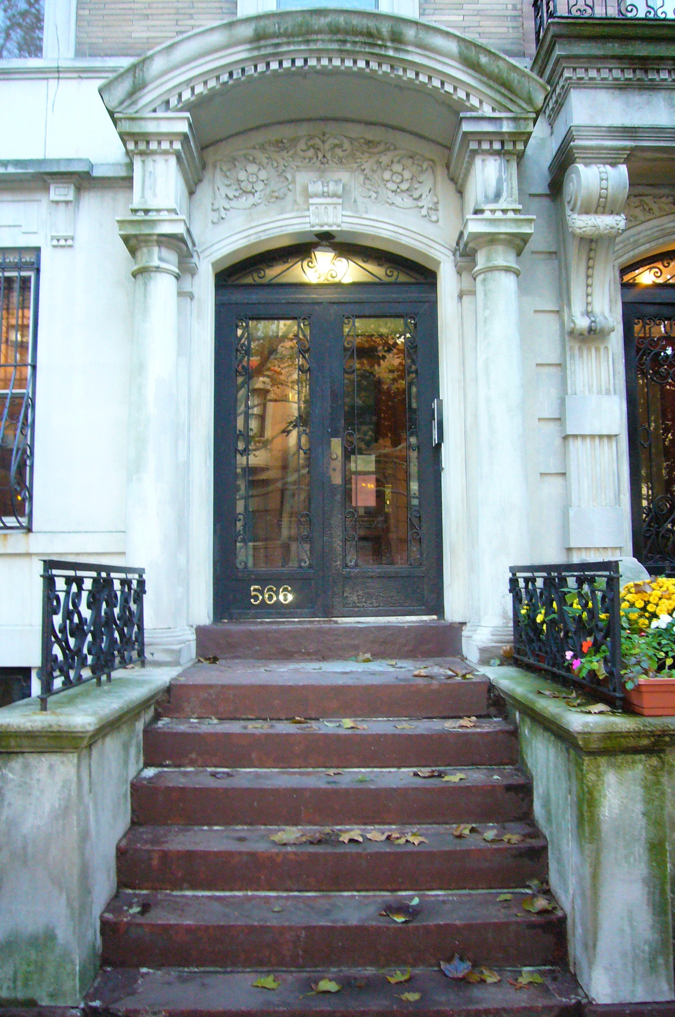 the front entrance of a mansion with two plants