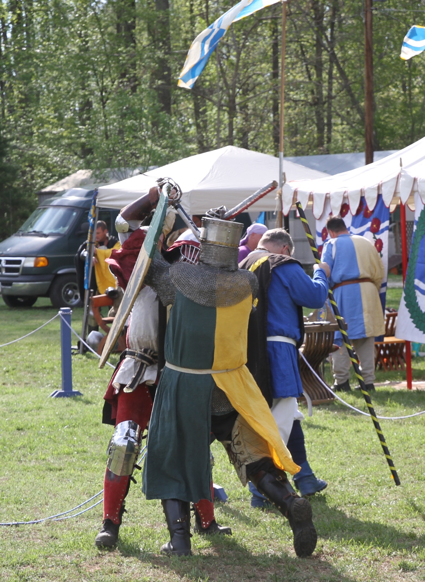 the knights fight in their medieval uniforms as flags fly over them