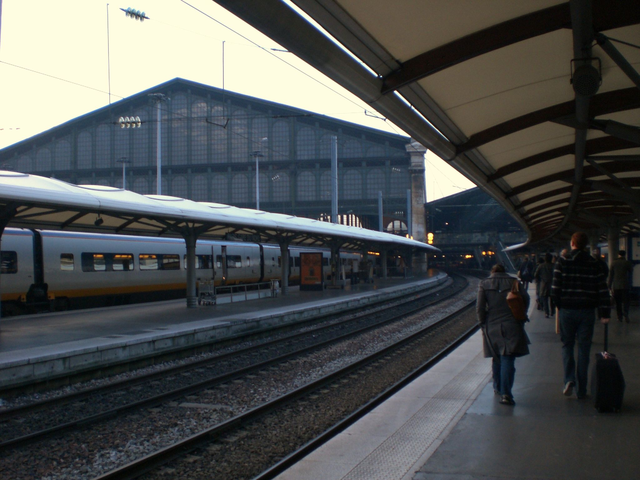 people wait on the platform as a train approaches