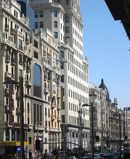 a large white building in a city next to other buildings