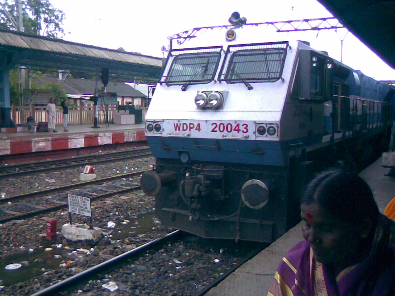 a blue and white train parked in front of a station