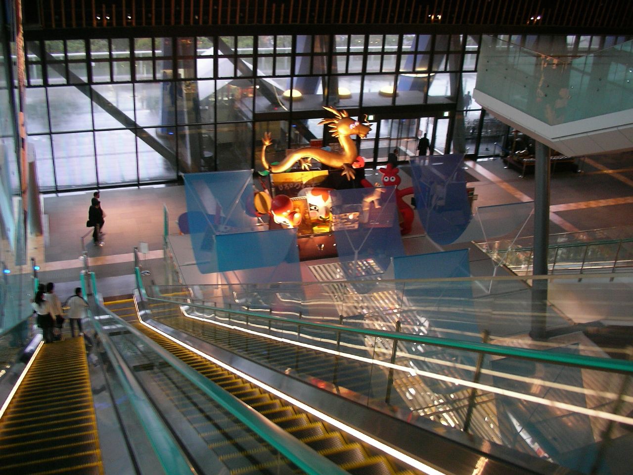 an escalator inside a building with people and sculptures