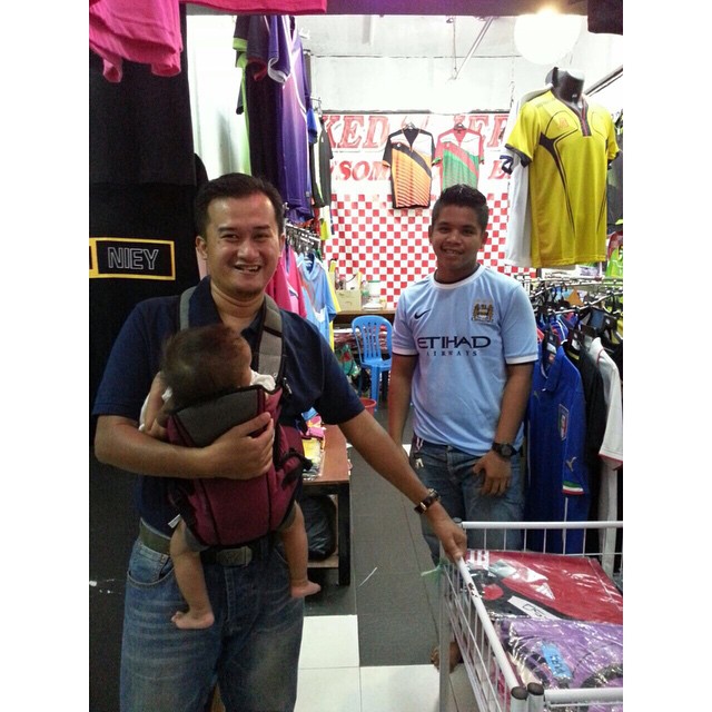 a man holds a baby while his two friends shop