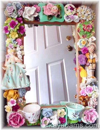 a mirror frame with flowers and dolls on it