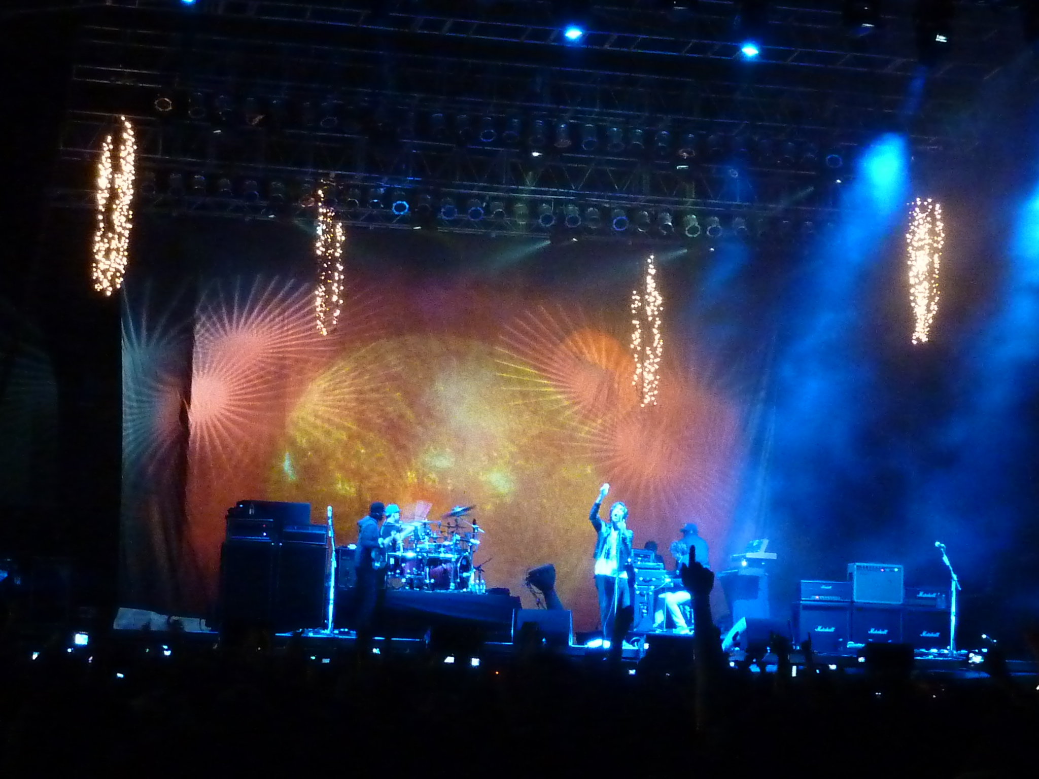 stage lights, a guitar player and band perform in front of an audience