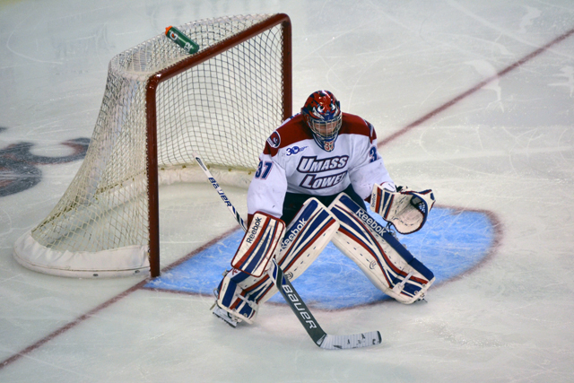 a hockey goalie sitting on the ice with his net on