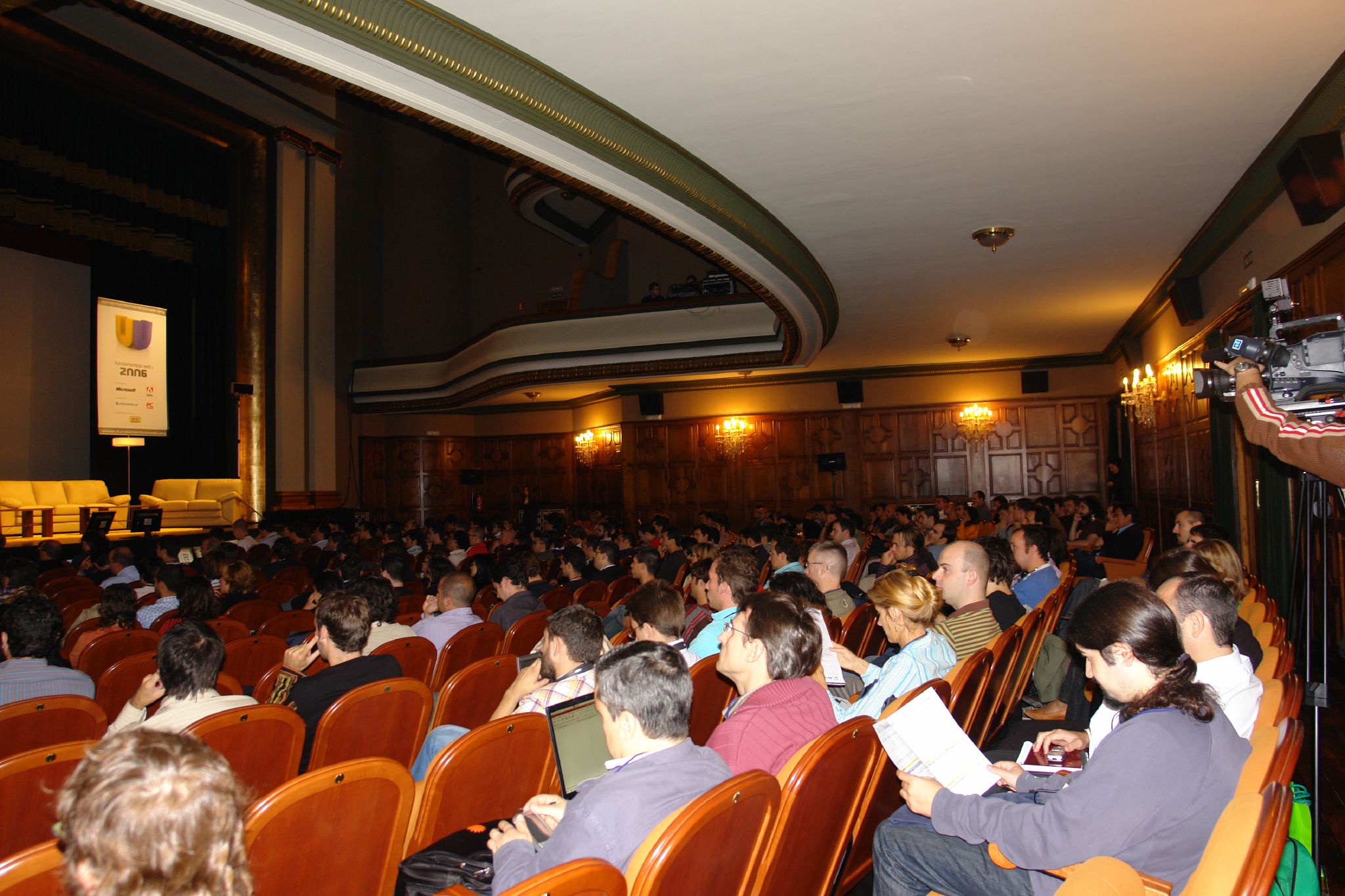a large group of people sitting in chairs at the front of a hall