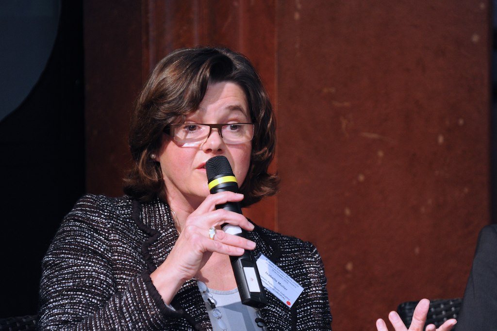 a woman talking into a microphone with a label on it