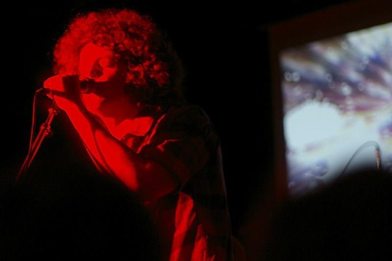 woman talking into a microphone standing next to a screen