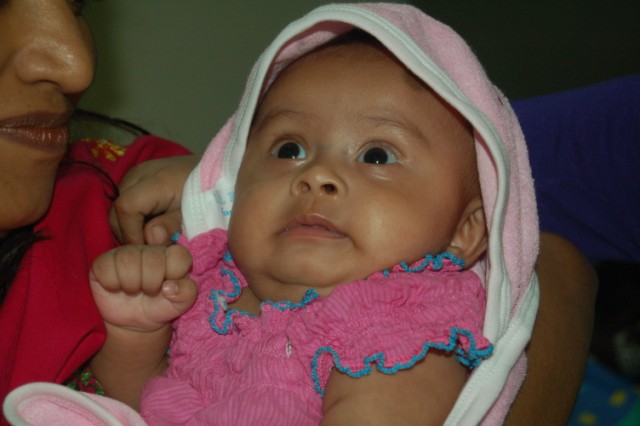 a baby wrapped in a pink and white hooded towel