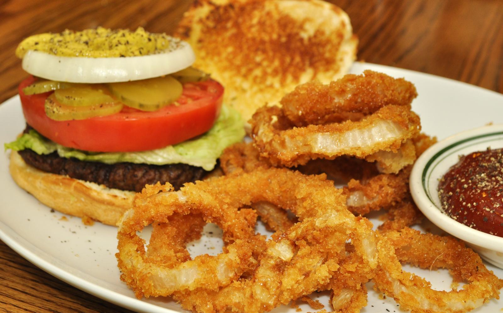 a plate has onion rings, a burger, and onion rings on it