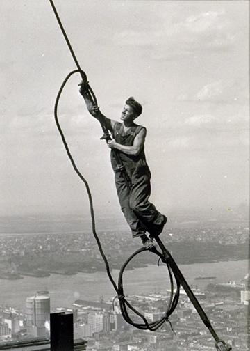 a man working on top of a building while holding onto a wire