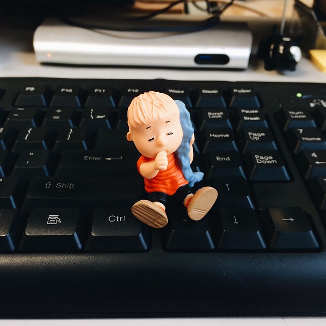 a figurine on the computer keyboard sitting next to the mouse