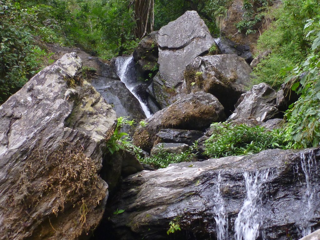 a stream surrounded by large rocks and trees