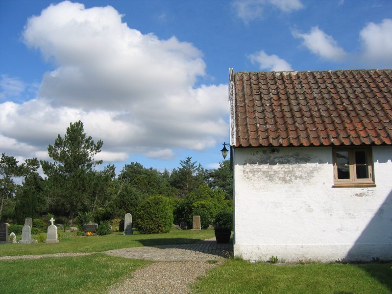 a small white house in a field with trees