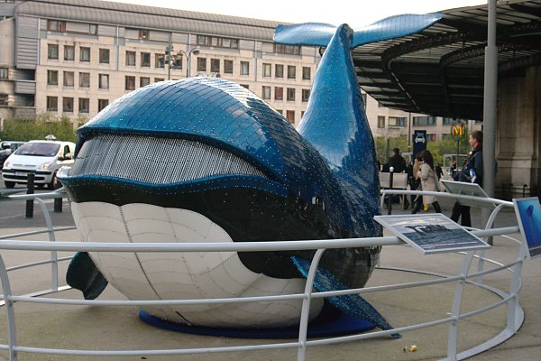 a sculpture of a whale at the entrance to a public transit station