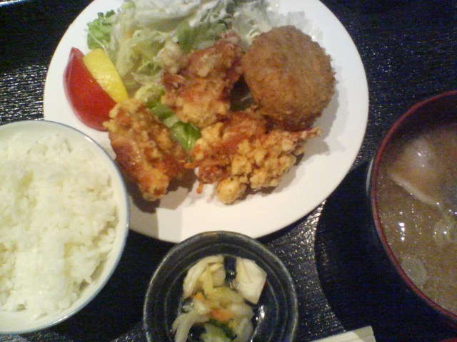 the plate of fried rice, vegetables and meat is beside a bowl of salad and water