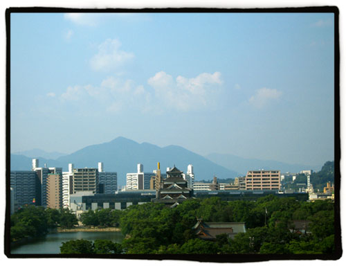 a scenic view of a city with mountains behind