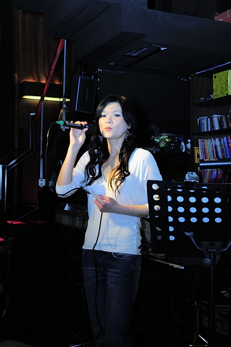 a woman is singing into a microphone in a darkened room